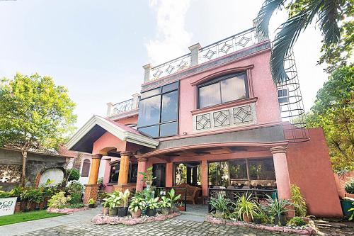 ein großes rosafarbenes Haus mit Fenstern und Pflanzen in der Unterkunft RedDoorz at Coco Grove Tourist Inn in Panglao