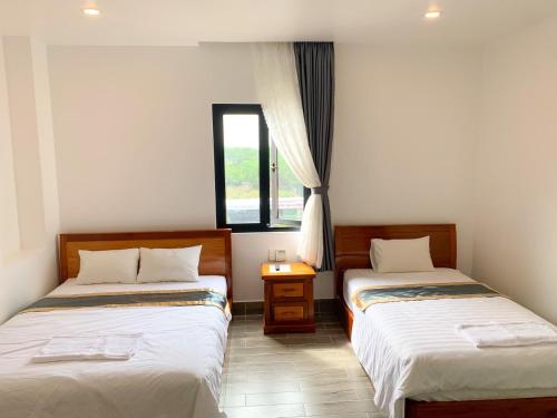 Habitación con 2 camas y ventana en Hotel Thiện Nhiên, en Hồng Ngự