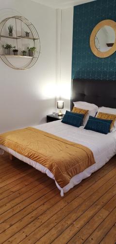 a bedroom with a large bed with two blue pillows at Logis Hotel La Tourelle du Beffroi in Bourbon-Lancy