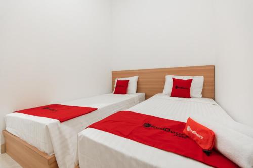 two beds with red pillows in a room at RedDoorz @ Graha Cemerlang Maros in Makassar