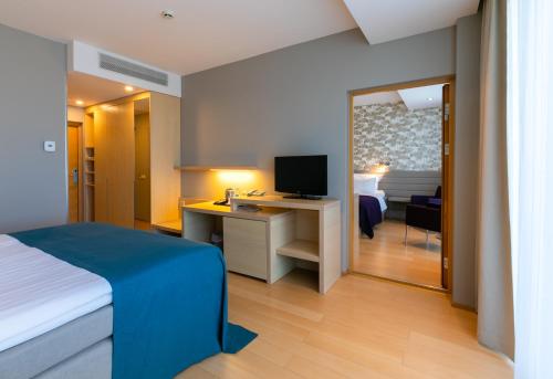 um quarto com uma cama e uma secretária com uma televisão em Spa Tervise Paradiis em Pärnu