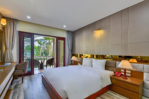 a bedroom with a large white bed and a desk at MANLI Resort Quảng Bình in Dong Hoi