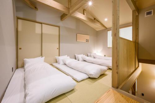 una fila de almohadas blancas en una habitación en HOTEL WOOD TAKAYAMA en Takayama