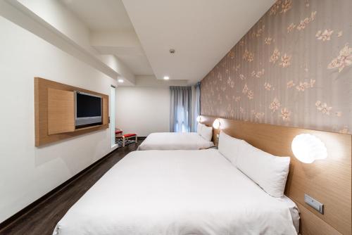 a hotel room with two beds and a tv at Fish Hotel - Yancheng in Kaohsiung
