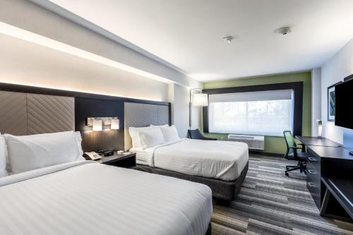 a hotel room with two beds and a flat screen tv at Holiday Inn Express & Suites Jersey City North - Hoboken by IHG in Jersey City