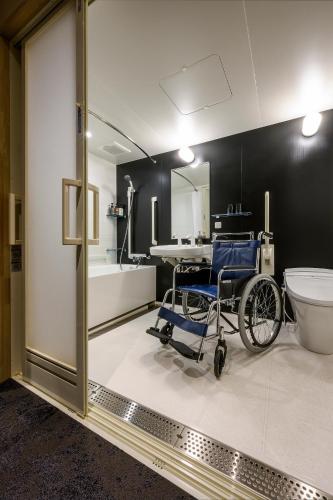 a wheelchair in a bathroom with a toilet and a sink at HOTEL WOOD TAKAYAMA in Takayama