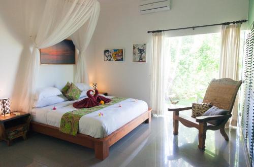 um quarto com uma cama, uma cadeira e uma janela em Villa Paradise Lovina em Temukus