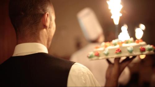 a man holding a cake with candles on it at Hotel Giulia in Lido di Camaiore