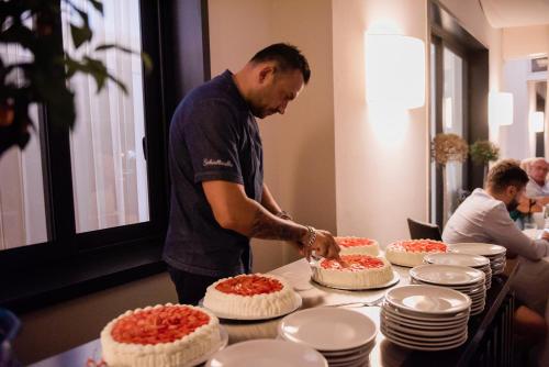 a man cutting into cakes on a table at Hotel Giulia in Lido di Camaiore