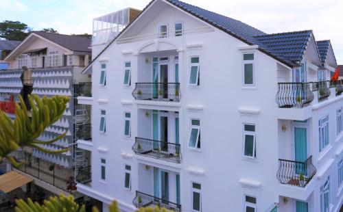a white apartment building with balconies and palm trees at Dalat Eco Hotel in Da Lat