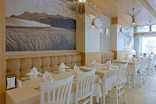 a dining room with white tables and white chairs at Xperia Saray Beach Hotel in Alanya