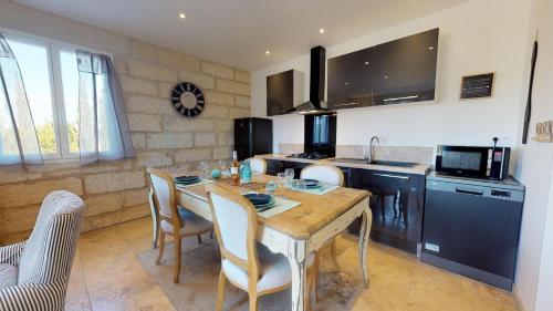 - une cuisine avec une table en bois, des chaises et un évier dans l'établissement Le Mas de Guiguite, à Mézoargues
