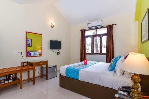 a bedroom with a bed and a desk and a window at Meadow View Resort in Majorda