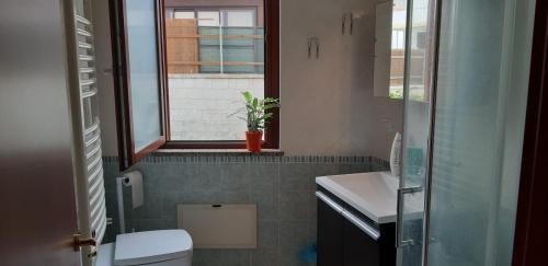a bathroom with a toilet and a sink and a window at Villa Rosa in SantʼAntìoco
