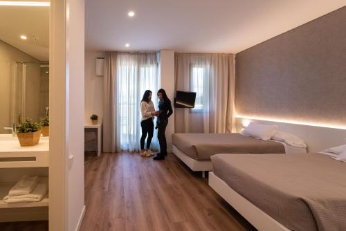 two people standing in a hotel room with two beds at Hotel Las Terrazas in Burgos