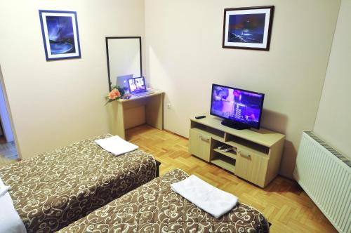 a room with two beds and a flat screen tv at Garni Hotel Lotos in Niš
