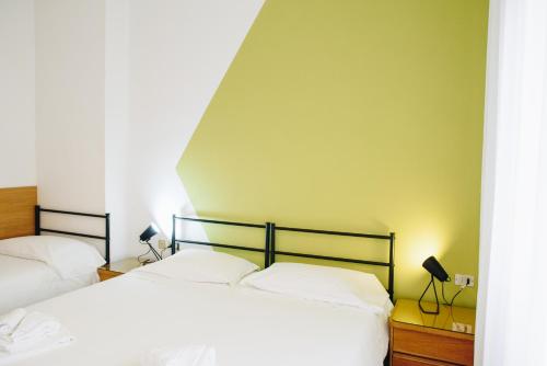 a bedroom with a bed and a lamp on the wall at UniHo Hostel in Pavia