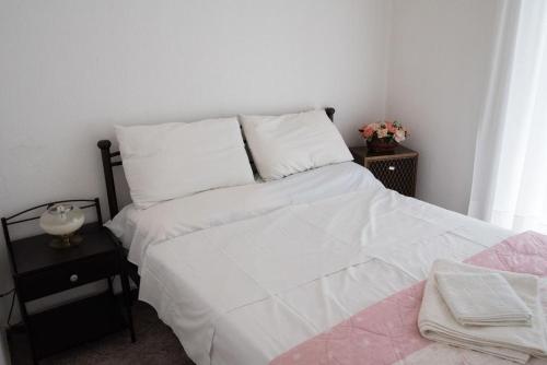 a bedroom with a bed with white sheets and a table at Niki seaview apartment in Porto Rafti