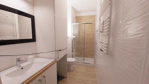 biała łazienka z toaletą i umywalką w obiekcie Central Apartments Ogrody 1 & Parking w Gdańsku