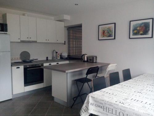 a kitchen with white cabinets and a table with chairs at Cozy House Mētriņi in Ķekava