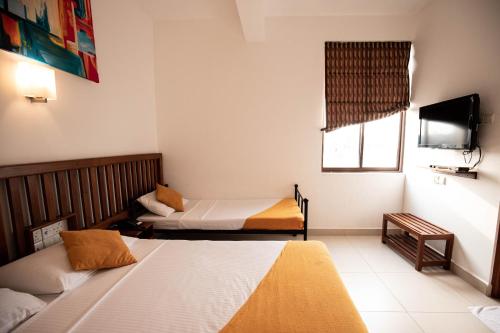 a hotel room with two beds and a television at Port View City Hotel in Colombo