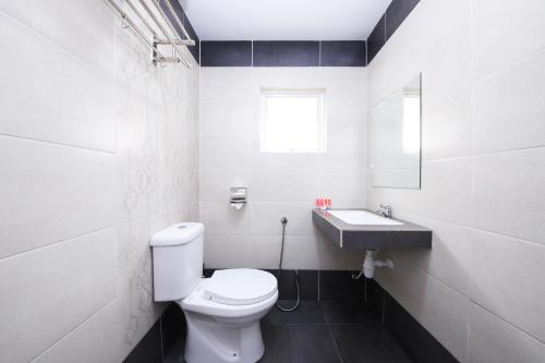 a white bathroom with a toilet and a sink at Beryll Inn Cyberjaya Hotel in Cyberjaya