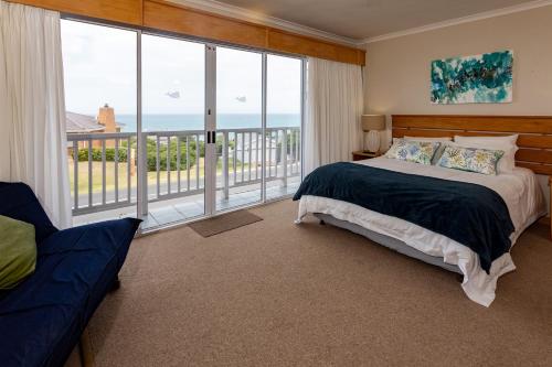 a bedroom with a bed and a large window at Aire del Mar Guest House in Gansbaai