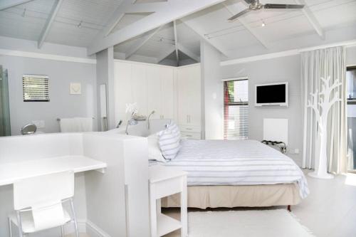 um quarto branco com uma cama, uma secretária e uma banheira em Whalejoy - A glimpse of heaven em Plettenberg Bay