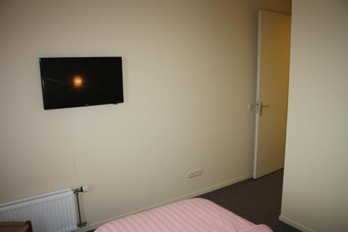 Habitación con cama y TV en la pared. en Hotel Café Restaurant Snackbar Beerzerveld, en Beerzerveld
