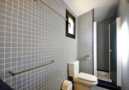 a bathroom with a toilet and blue tiled walls at VILLA AUREA-Cala Mesquida- Primera linea de Mar in Cala Mesquida