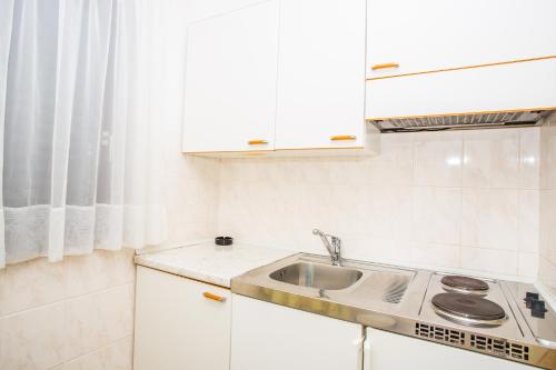 a white kitchen with a sink and a window at Apartmani Pava in Omiš