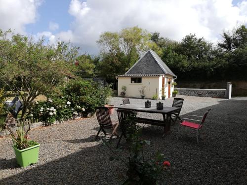 a patio with a table and chairs and a house at La Parisiere in Gavray