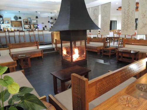 a restaurant with a fireplace in the middle of the room at Plumeria Hotel in Antsirabe