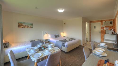 a hotel room with a bed and a table and chairs at Rosebourne Gardens Motel in Woolgoolga
