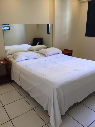 two beds in a room with white sheets and pillows at Porto de Iracema - Fortaleza houses in Fortaleza