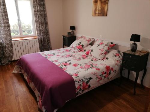 a bedroom with a bed with a floral bedspread at La Parisiere in Gavray