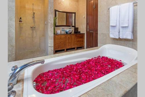 La salle de bains est pourvue d'une baignoire remplie de fleurs rouges. dans l'établissement Villa Deh Simba at Oberoi, à Seminyak