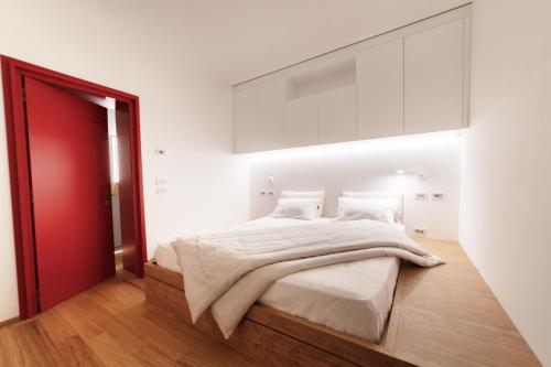 1 dormitorio con 1 cama grande y puerta roja en CaToo Dimora Di Design in Palazzo Nobiliare al Duomo, en Padua