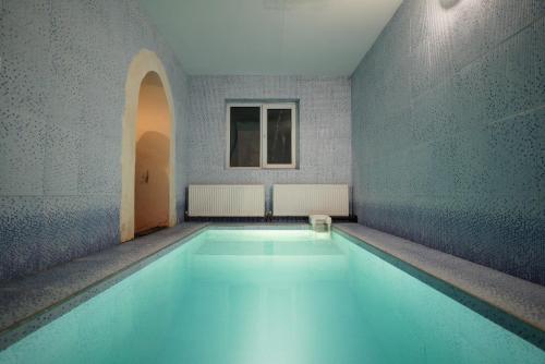 - une piscine dans un bâtiment avec un sol bleu dans l'établissement Hotel Usengi, à Elbrouz