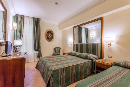 a hotel room with two beds and a mirror at Raeli Hotel Siracusa in Rome