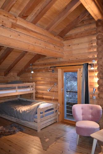 - une chambre avec un lit et une chaise dans une cabane en rondins dans l'établissement Le Chardonneret, à La Bresse