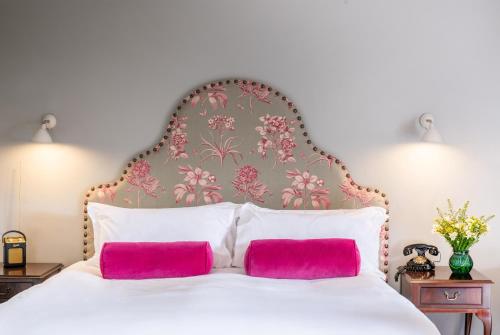 a bedroom with a large white bed with two pink pillows at Burley Manor in Burley