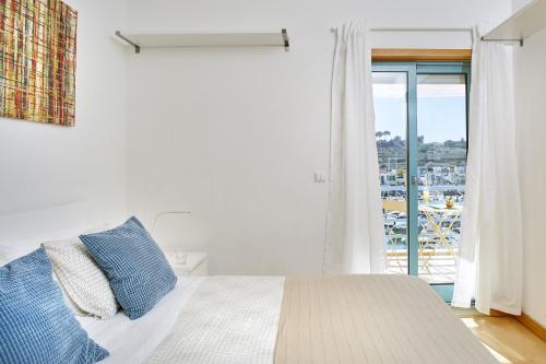 a white bedroom with a bed and a large window at Casas Barulho Albufeira Marina in Albufeira