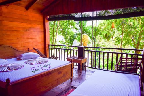 a bedroom with a bed and a balcony with a view at Rafters Retreat in Kitulgala