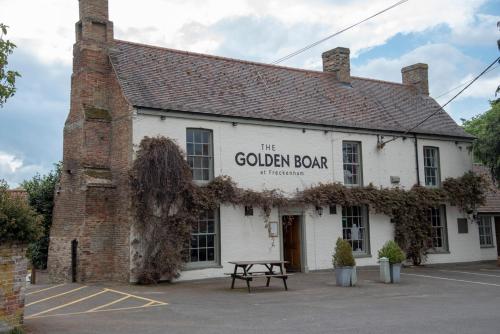 un edificio con un cartel que lee la barra dorada en The Golden Boar, en Newmarket