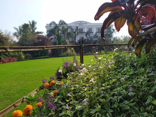 a garden with flowers in front of a building at La Franklin Hotel in Bhubaneshwar