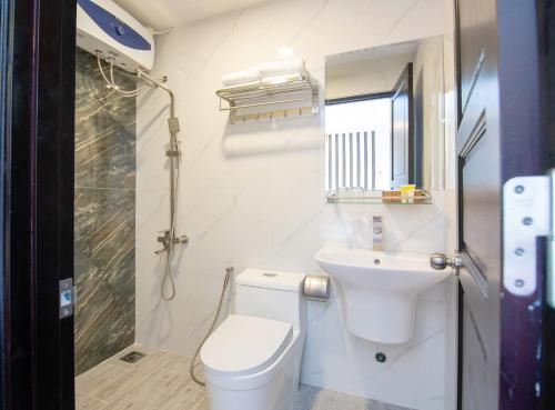 a white bathroom with a toilet and a sink at Villa Camellia in Da Lat