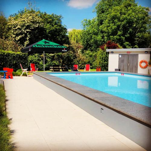 a swimming pool with an umbrella and a table and chairs at Novotel Rotterdam - Schiedam in Schiedam