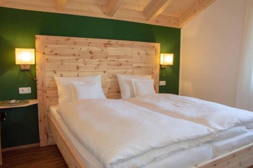 - une chambre avec un grand lit blanc et un mur vert dans l'établissement Bergkiefer - Ferienwohnung, à Oy-Mittelberg