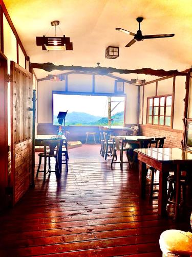 a dining room with tables and chairs and a large window at Yuan Fang Homestay in Fanlu